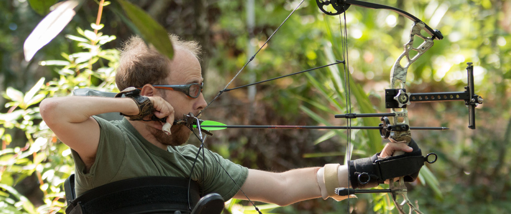 profile image of a man practicing archery in the woods